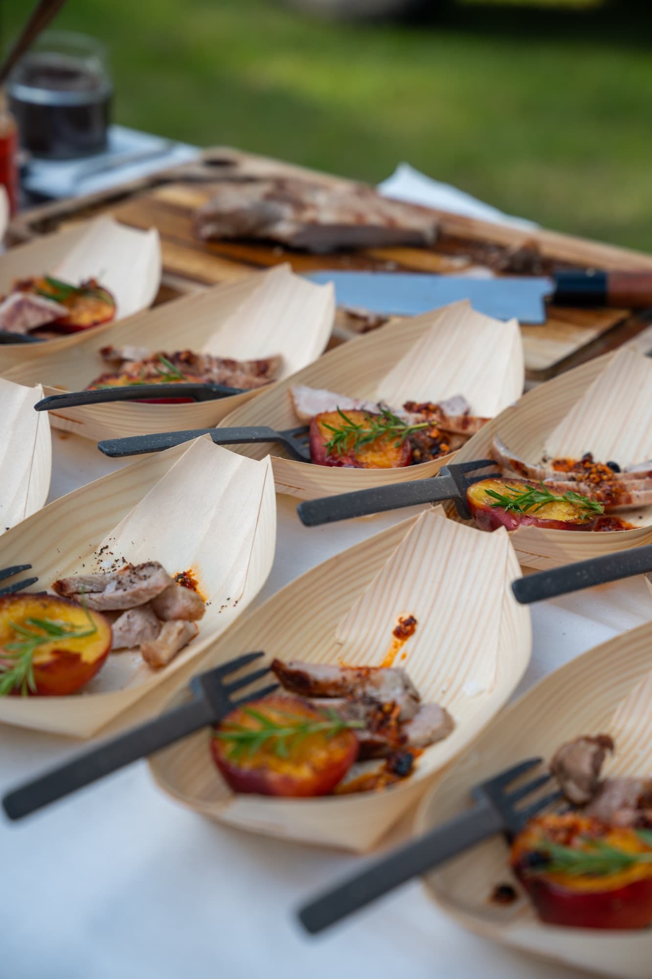 Edel gedeckte lange Tafel im Freien, Fleisch am offenen Feuer, warmes Licht